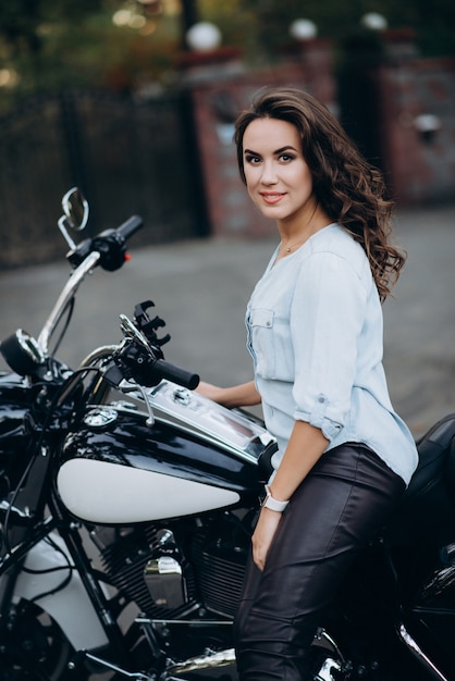 Garota jovem motociclista linda de camisa azul em uma motocicleta. o conceito de velocidade e liberdade