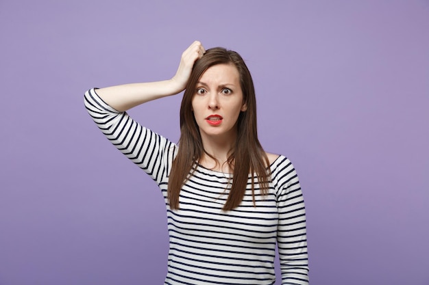 Garota jovem perplexa perplexa em roupas listradas casuais posando isolado no retrato de estúdio de fundo de parede roxa violeta. conceito de estilo de vida de pessoas. mock up espaço de cópia. colocando a mão na cabeça.