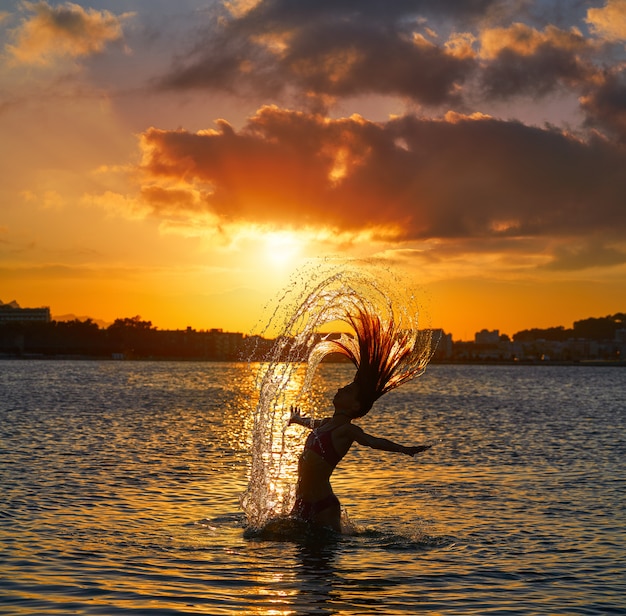 Garota lançando cabelo flip na praia do sol