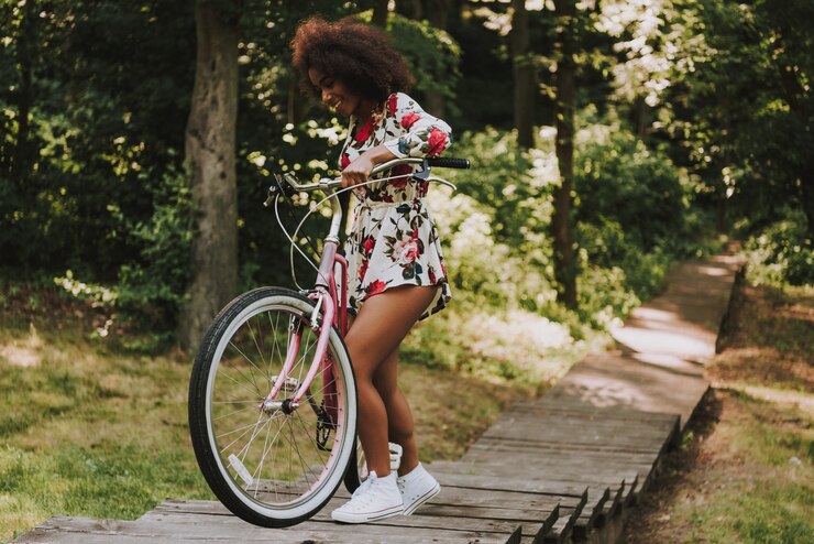Foto garota latina está rolando a bicicleta na passarela de madeira.
