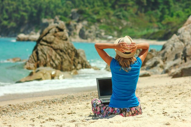 Garota legal e feliz com laptop perto do conceito de trabalho remoto do mar