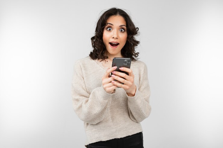Garota legal em uma blusa branca com um smartphone na mão em um branco com espaço de cópia