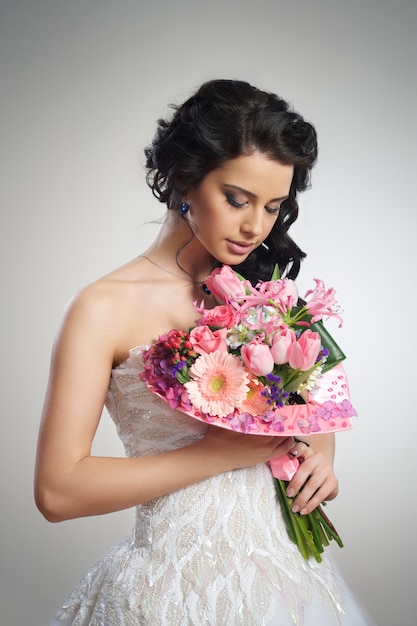 garota linda em um vestido de noiva branco com um buquê de flores