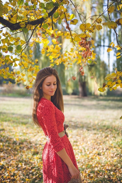 Garota linda em um vestido vermelho em um parque de outono