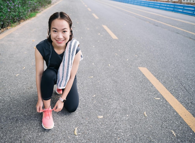 Garota linda feliz preparar sapato para exercício de corrida no parque ao ar livre