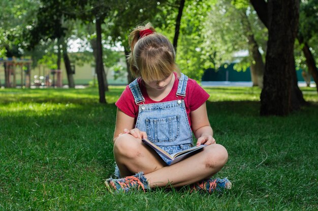 Garota loira com livro na grama verde