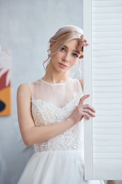 Garota loira em um lindo vestido de noiva branco. noiva mulher está esperando o noivo antes do casamento