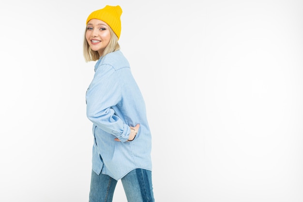 Garota loira em uma camisa jeans elegante e um suéter amarelo sobre um fundo branco, com espaço de cópia