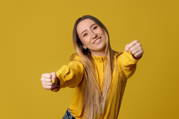 Foto garota loira feliz fingindo andar de carro em fundo amarelo