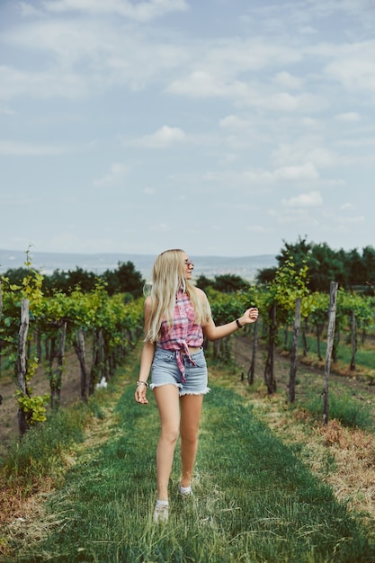 Garota loira modelo com corpo perfeito esbelto em shorts jeans e camisa sem mangas, andando na zona rural. viagem de verão