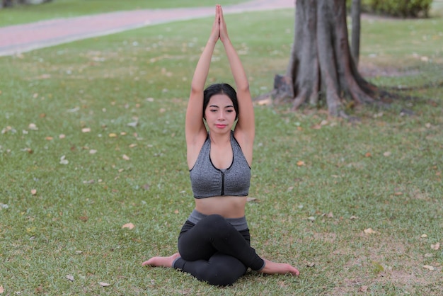 Garota magra joga ioga no gramado do parquerelax em nutureAsian Girls adoram saúde praticando ioga