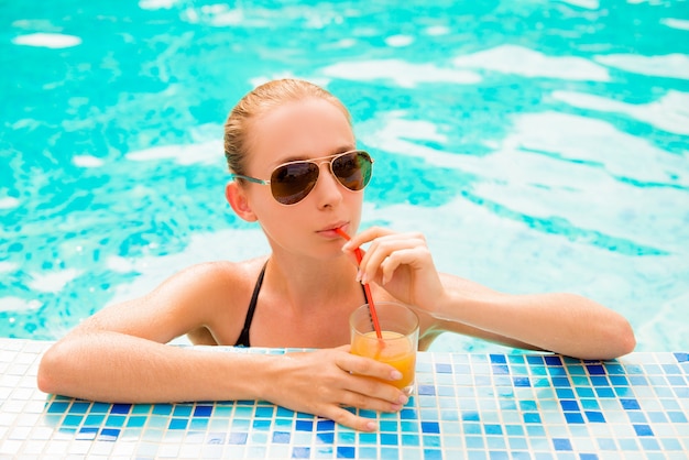 garota magra nadando em uma piscina com suco