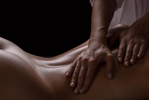 Garota massagista faz uma massagem fechada em uma massagem de fundo escuro