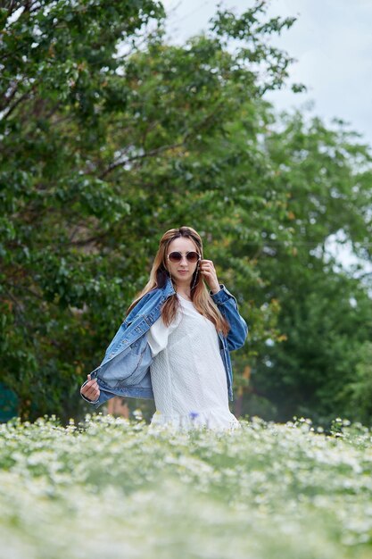 Garota milenar elegante e elegante no campo de camomila relaxando Conectando-se com a natureza Estética de verão