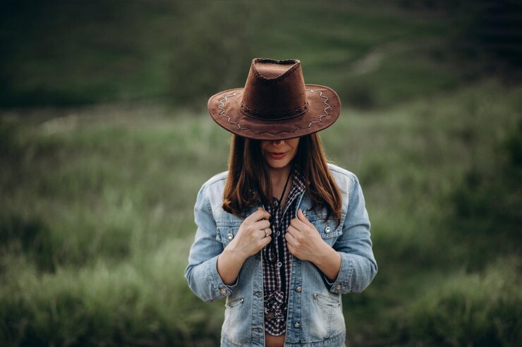 Foto garota misteriosa esconde o rosto atrás de um chapéu de cowboy garota sozinha no campo à noite segura uma jaqueta jeans como se estivesse congelada na cabeça chapéu de cowboy