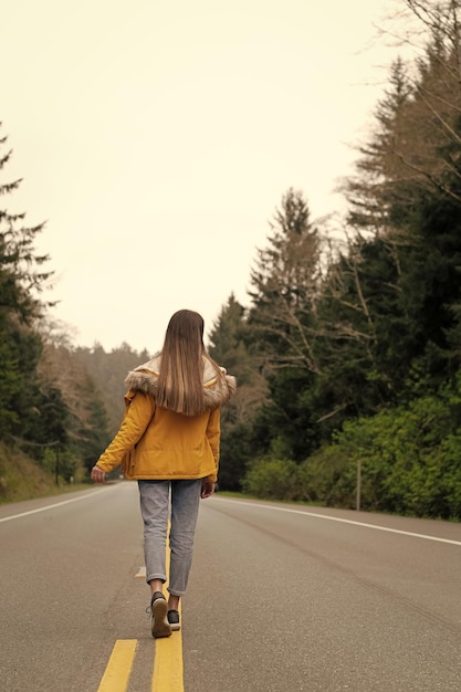 Foto garota mochileiro vista traseira no casaco andando em viagens rodoviárias