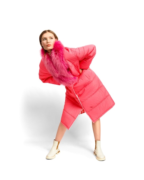 Garota modelo de moda em um elegante casaco rosa posando em um fundo branco