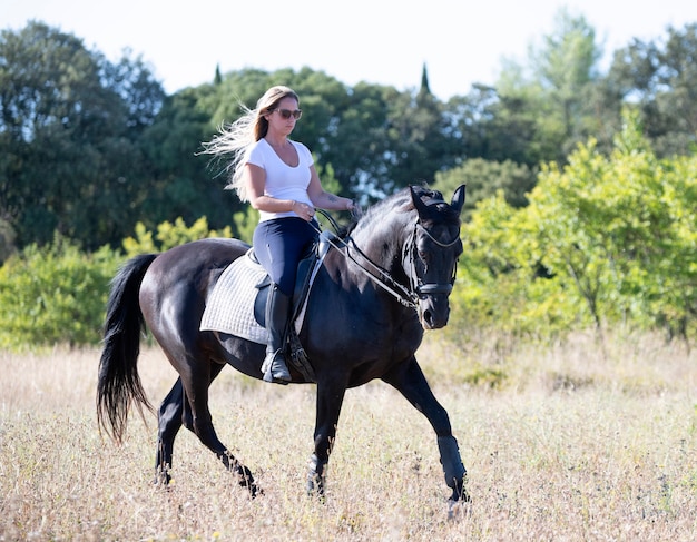 Garota montando está treinando seu cavalo preto