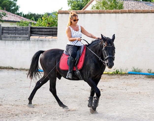 Garota montando está treinando seu cavalo preto