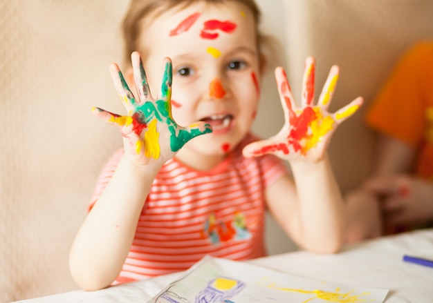 Garota mostrando as mãos pintadas. Mãos pintadas em tintas coloridas. Conceito de educação, escola, arte e painitng.