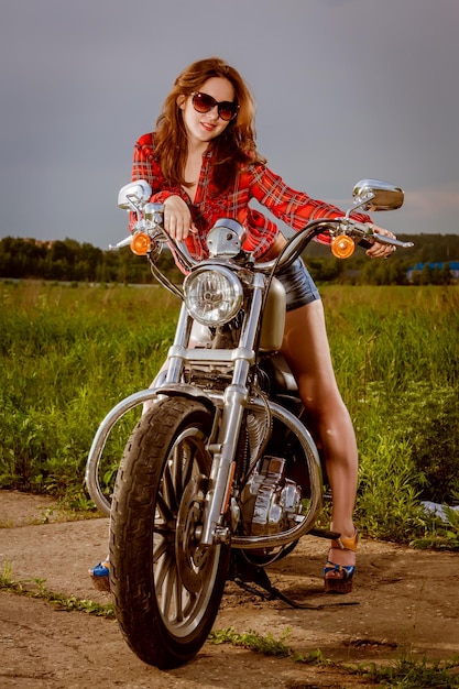 Garota motociclista com óculos de sol e moto