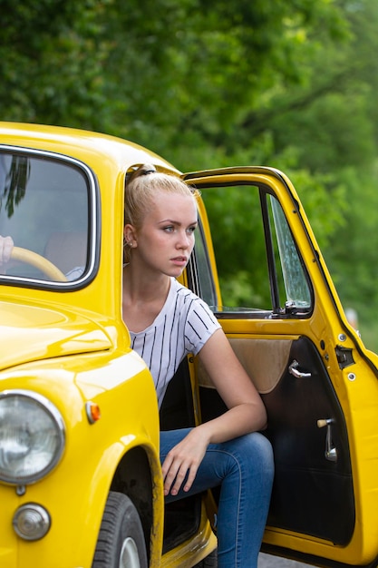 Garota motorista de mulher no estilo de automóvel de moda antiga de carro retrô