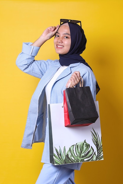 Garota muçulmana adora fazer compras, usando estilo casual e óculos escuros, olhando para a câmera e posando