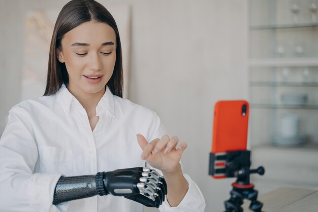 Garota muito deficiente é o blogueiro Amputee está gravando vídeo como usar o braço cibernético mecânico