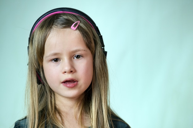 Garota muito sorridente cild ouvindo música em grandes fones de ouvido rosa.