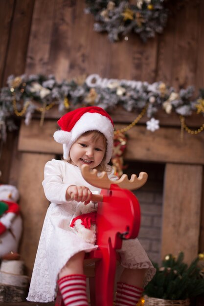 Garota na árvore de natal com presentes, montando um brinquedo los