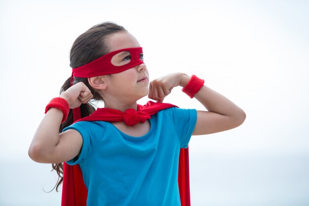 Garota na fantasia de super-herói, flexionando os músculos