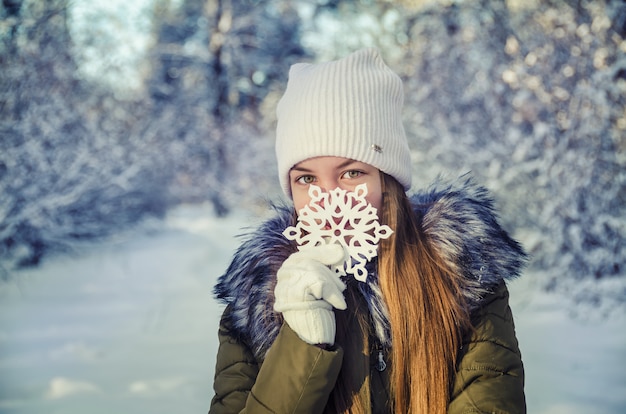 Garota na floresta de inverno posando com floco de neve
