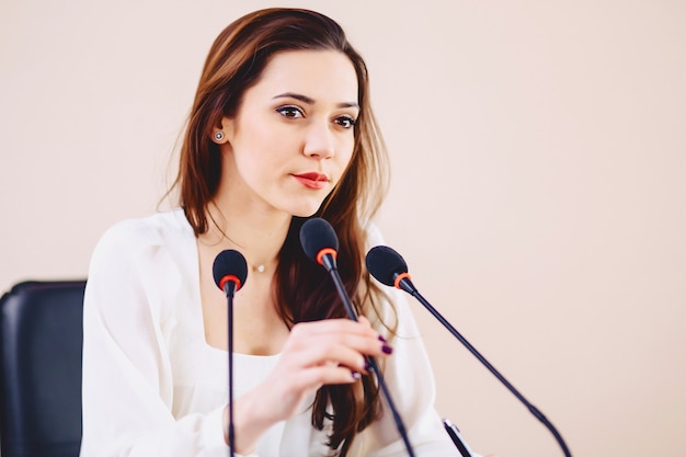 Garota na mesa fala em microfones na sala de conferências