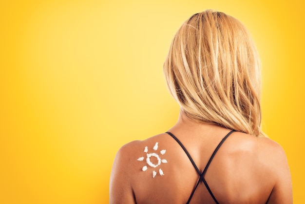 Garota na praia de maiô com um sol feito de protetor solar