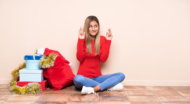 Garota nas férias de Natal, sentada no chão com os dedos cruzando