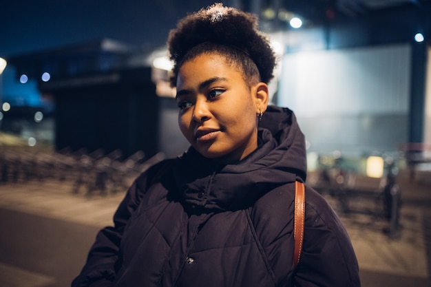 Garota negra posando na rua e olhando em linha reta