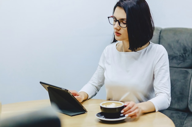 Garota no café bebe café e funciona em tablet