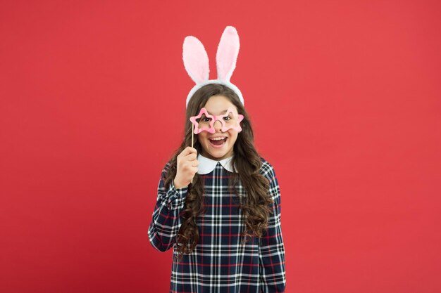 Garota no coelhinho da Páscoa durante a caça aos ovos. conceito de festa e criança. férias em família de primavera. coelhinho fofo. retrato de criança com óculos de festa. se divertindo. garoto engraçado usa orelhas de coelho.