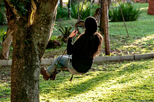 Garota no jardim balançando no balanço da árvore