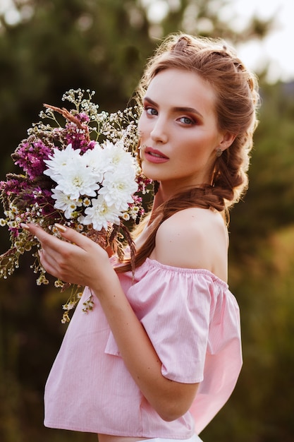 garota no jardim de verão. segurando um buquê de flores silvestres