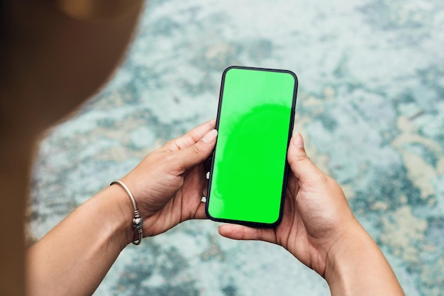 Garota no parque segurando um smartphone com tela verde Área verde de ponte de madeira e um lago artificial Chroma Key