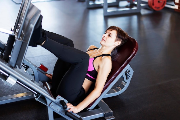 Garota no simulador na academia fazendo exercício