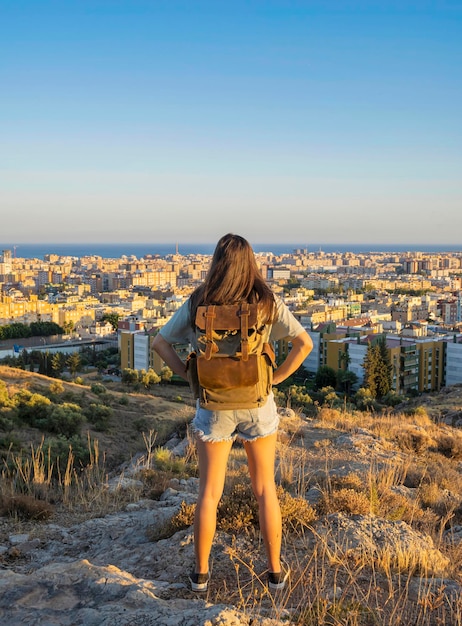 Garota nômade digital olhando para a cidade de Málaga ao pôr do sol