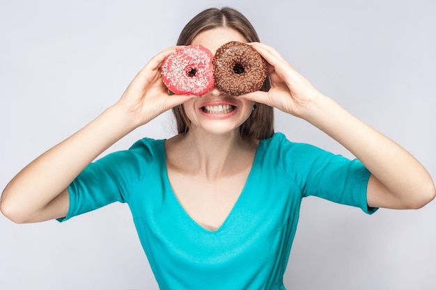 Garota olhando através de rosquinhas gosta de fazer óculos em fundo cinza