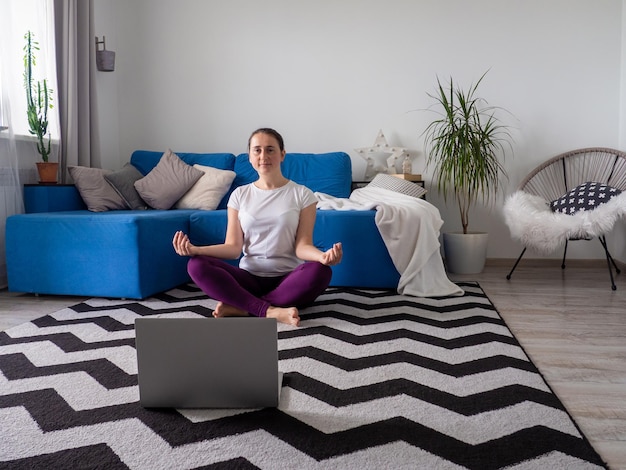 Garota olhando no laptop durante a prática de ioga em casa