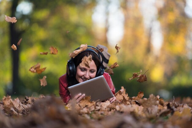 Garota ouvindo música nas folhas de outono