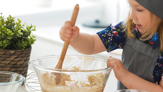 Garota padeira mistura a mistura para biscoitos com um batedor de perto