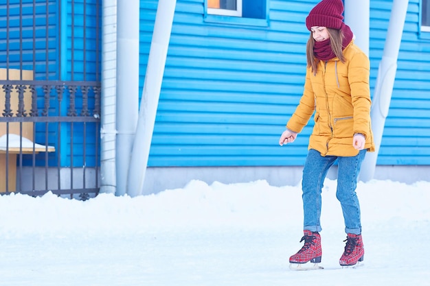 Garota patina no inverno no gelo perto de uma instalação esportiva