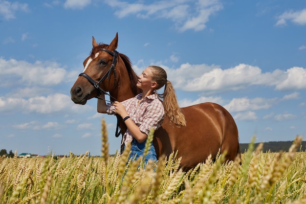 Garota piloto fica ao lado do cavalo no campo