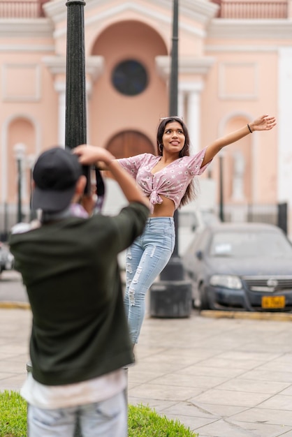 Garota posando com gestos divertidos enquanto um amigo tira fotos dela ao ar livre